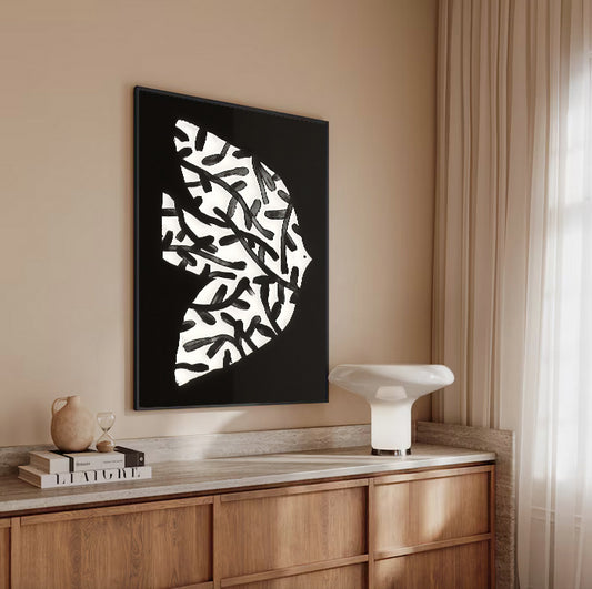Modern interior with abstract black and white artwork on a beige wall above a wooden cabinet.