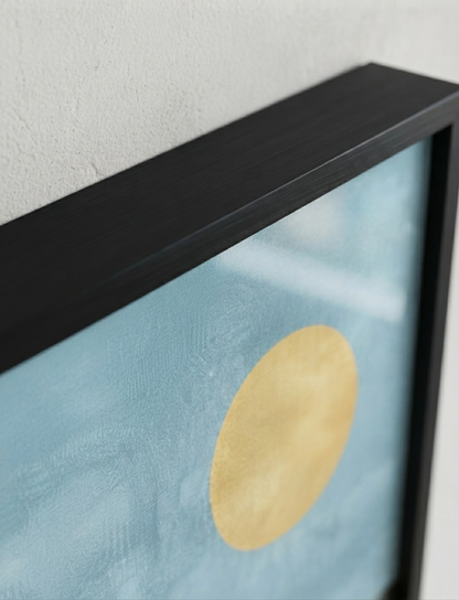 Close-up of a Bauhaus style swimming pool architectural print inspired by Palm Springs architecture featuring a textured light blue background with a large gold circular motif and a thick black frame against a white wall.
