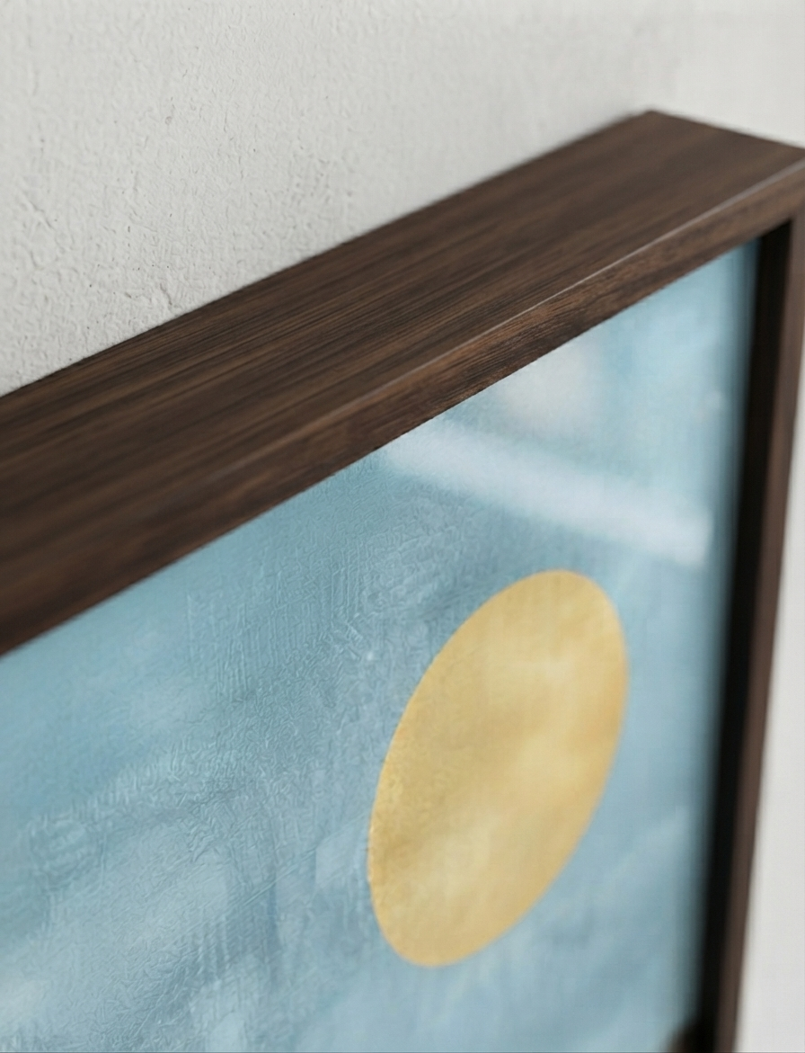 A close-up of framed  Bauhaus style swimming pool architectural print with mid-century wall art showing a dark brown wood frame, a textured light blue background, and a large circular gold medallion.