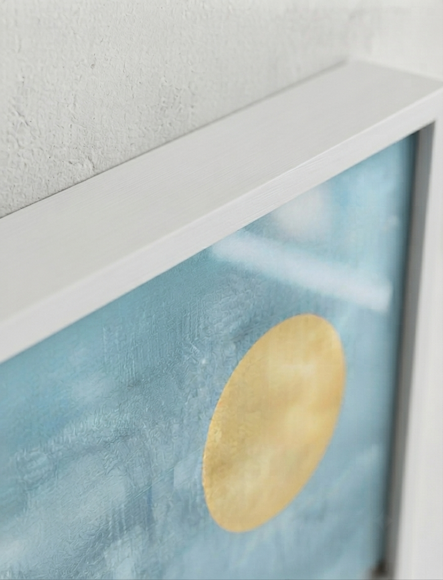 Close-up of framed Bauhaus style swimming pool architectural print for architectural wall décor showing a textured light blue background with a large gold circular motif and a white frame against a light wall.