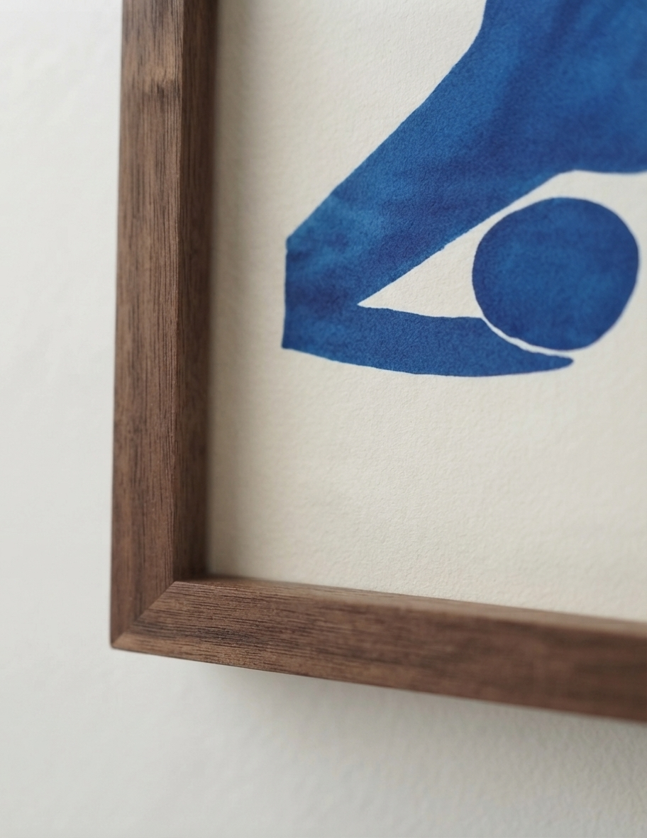 Close-up of a framed  Fauvist Style Female Figure Art Print by PrintHaus showing a dark brown wooden frame corner and a blue abstract illustration on textured off-white paper.