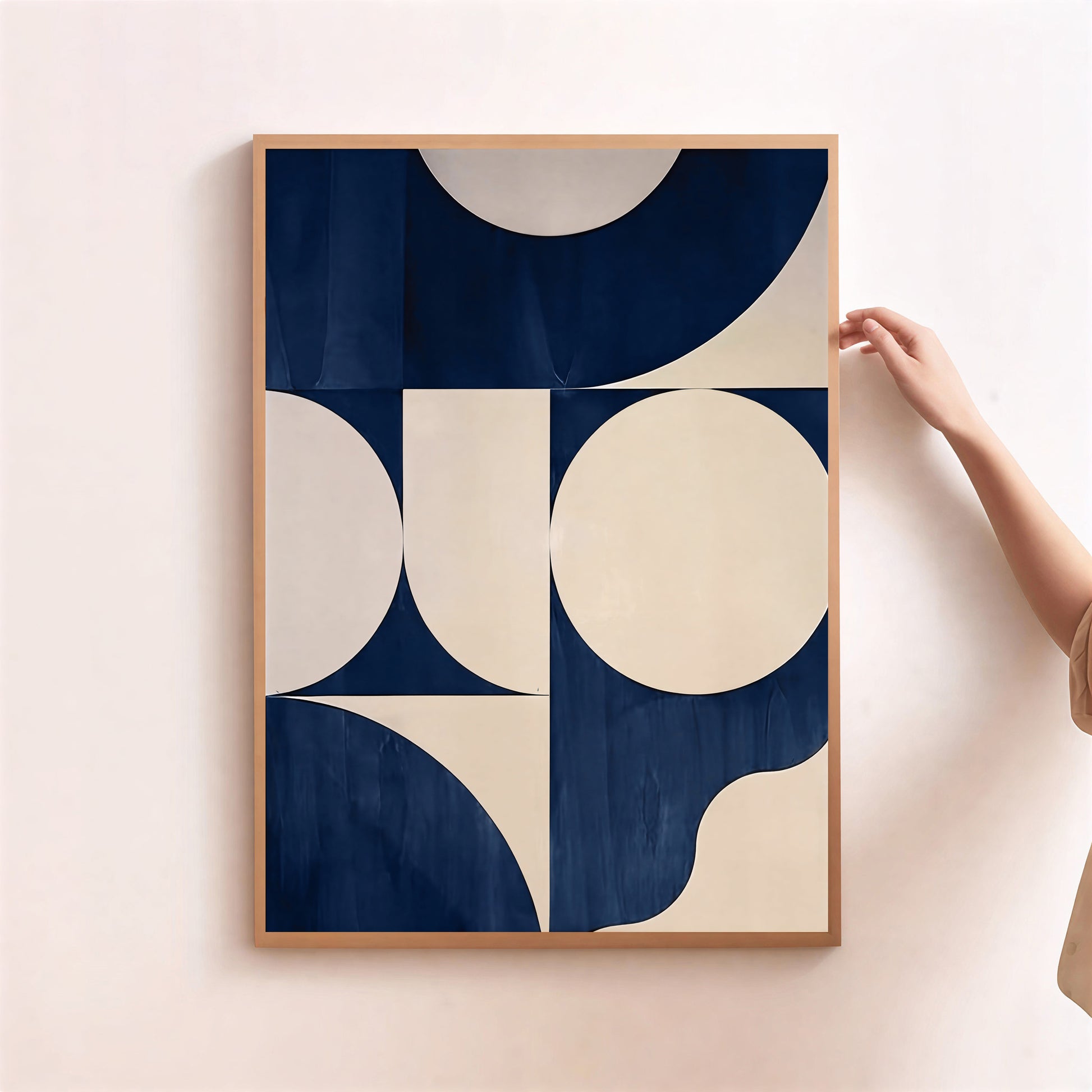 Framed abstract art print with geometric shapes on a light pink wall.