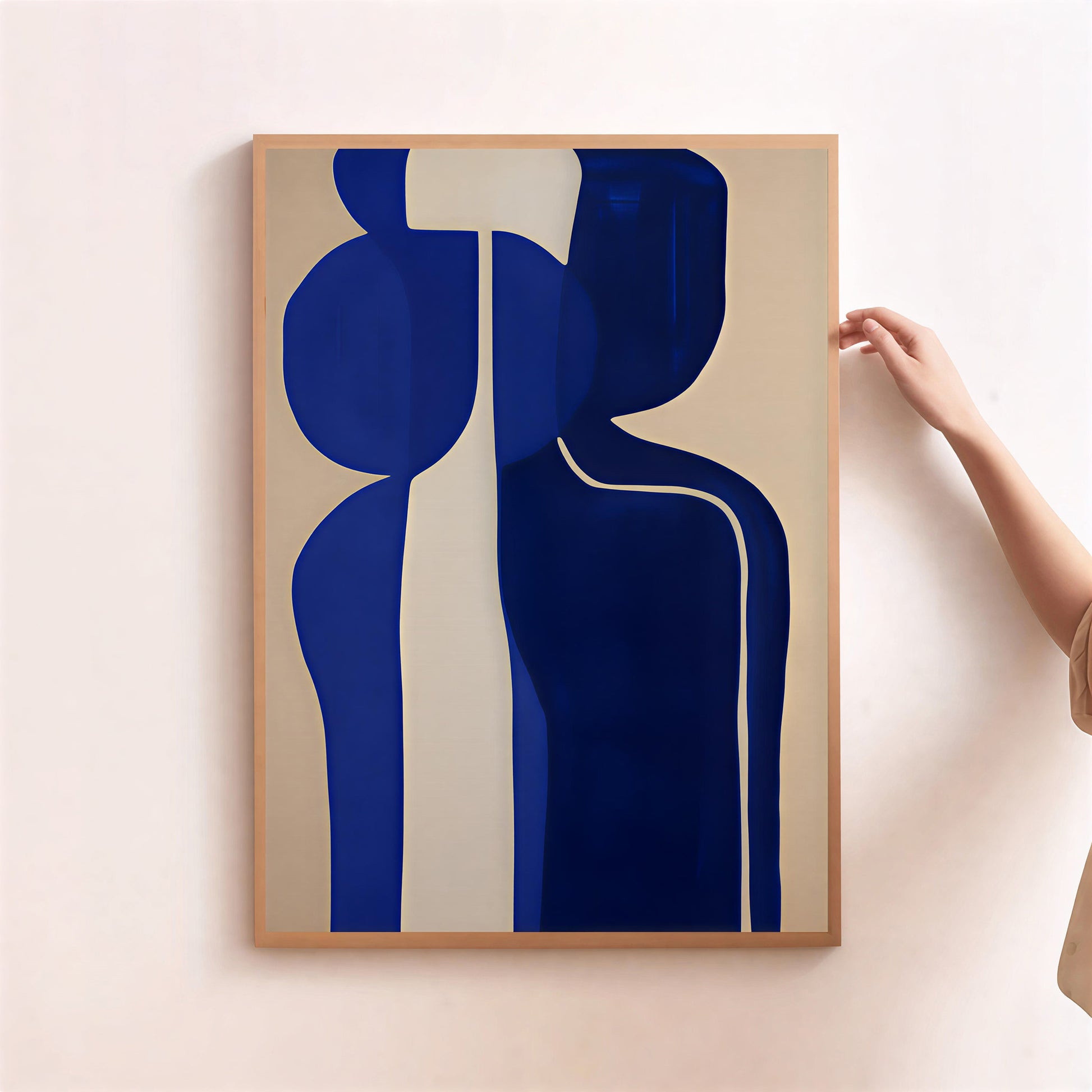 Abstract art print with blue shapes on a beige background, held by a hand.