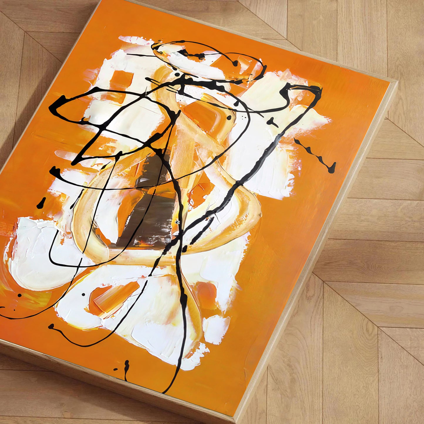 Abstract painting with orange, white, and black on a wooden floor