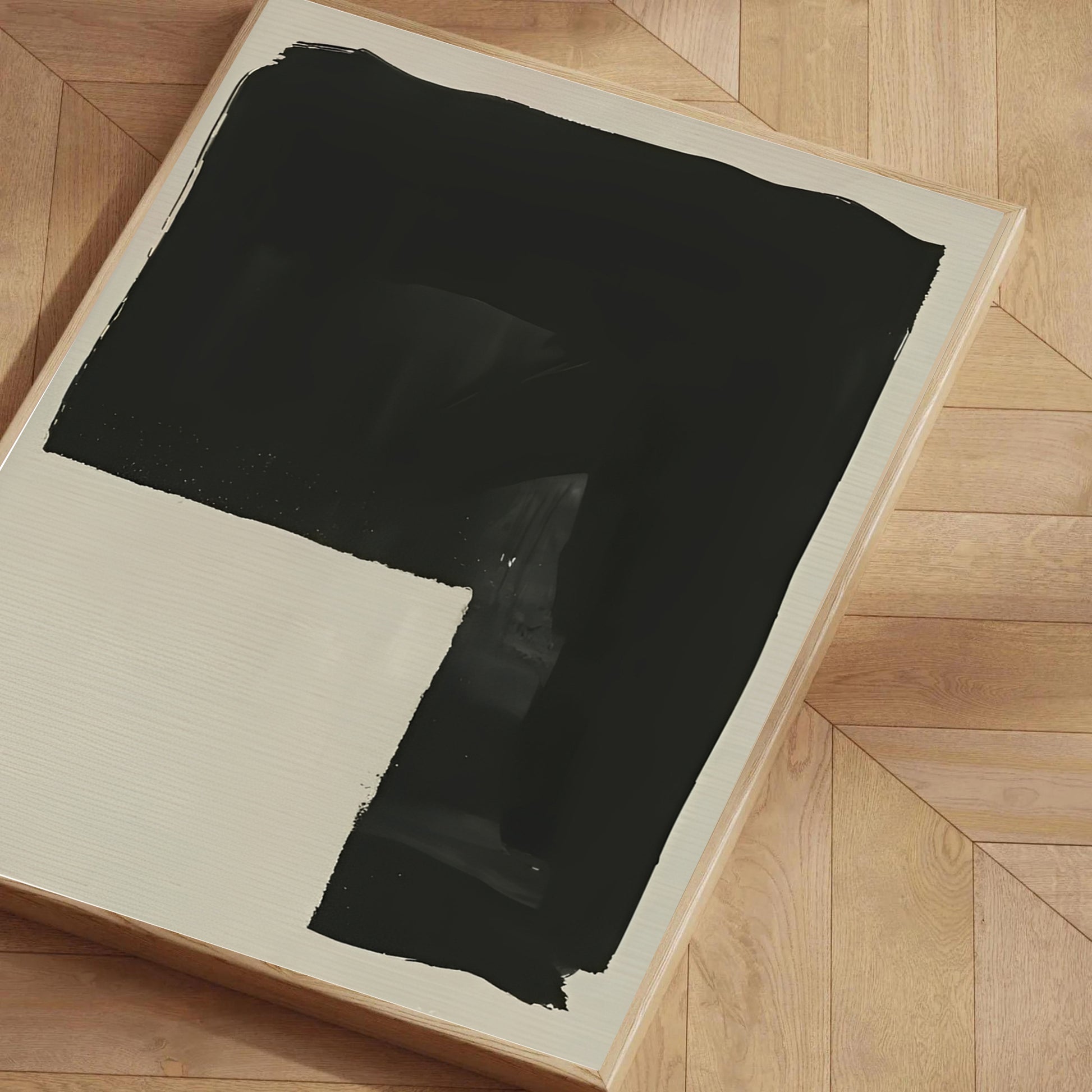 Black abstract painting on a beige canvas with a wooden floor background