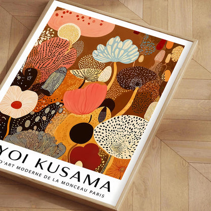 Framed artwork with abstract floral design and 'Yoyi Kusama' text on a wooden floor.