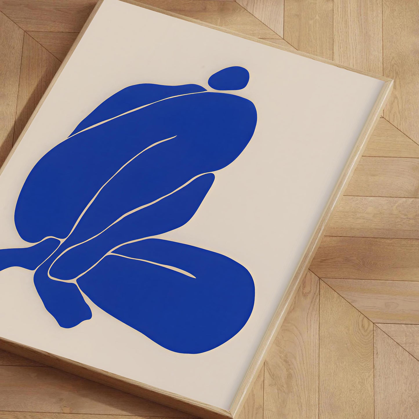 Abstract blue artwork on a beige background with a wooden frame, placed on a wooden floor.