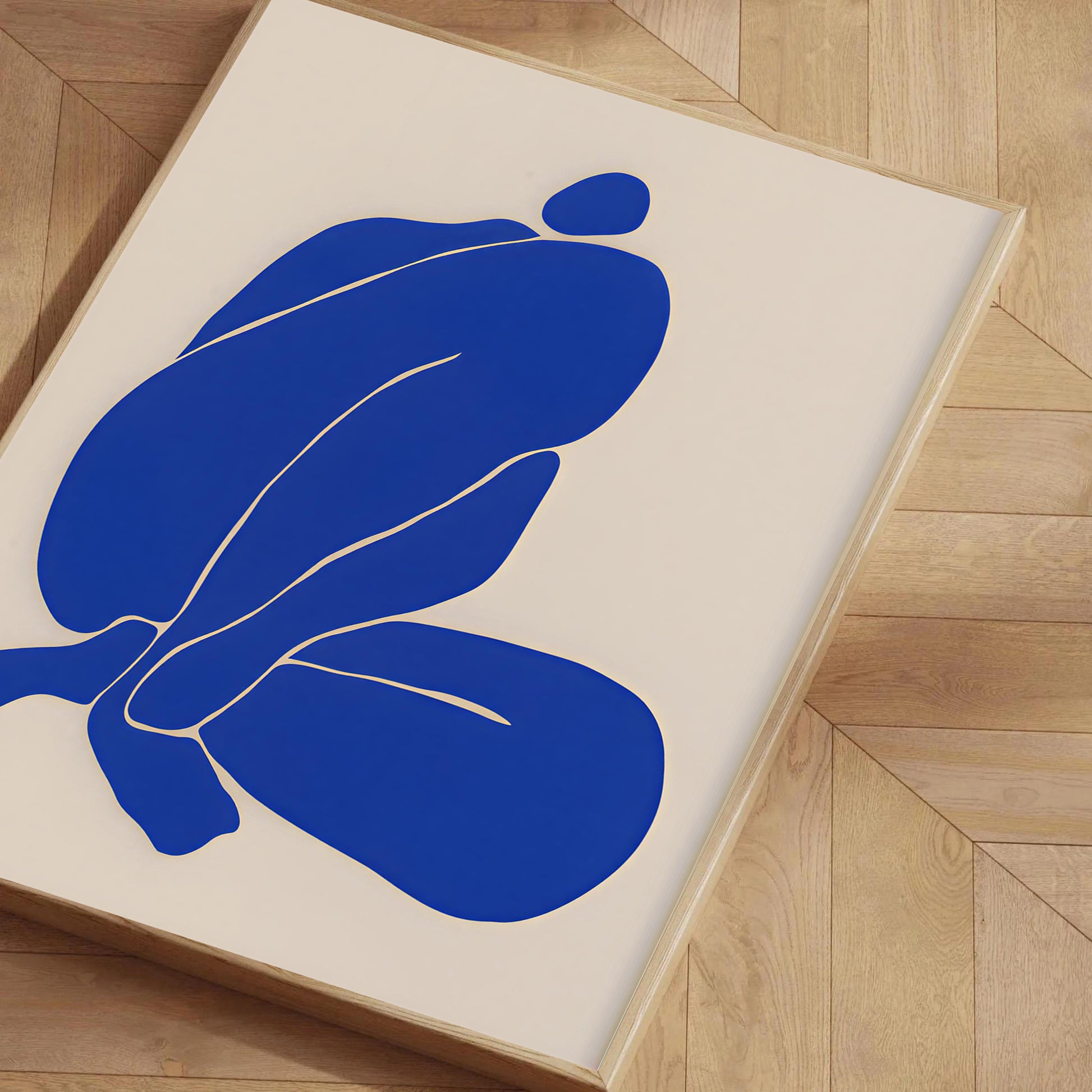 Abstract blue artwork on a beige background with a wooden frame, placed on a wooden floor.