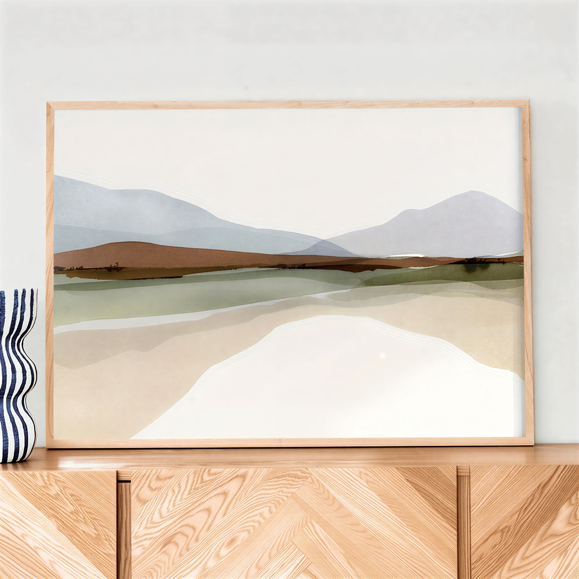 Framed landscape print on a wooden surface with a white wall background