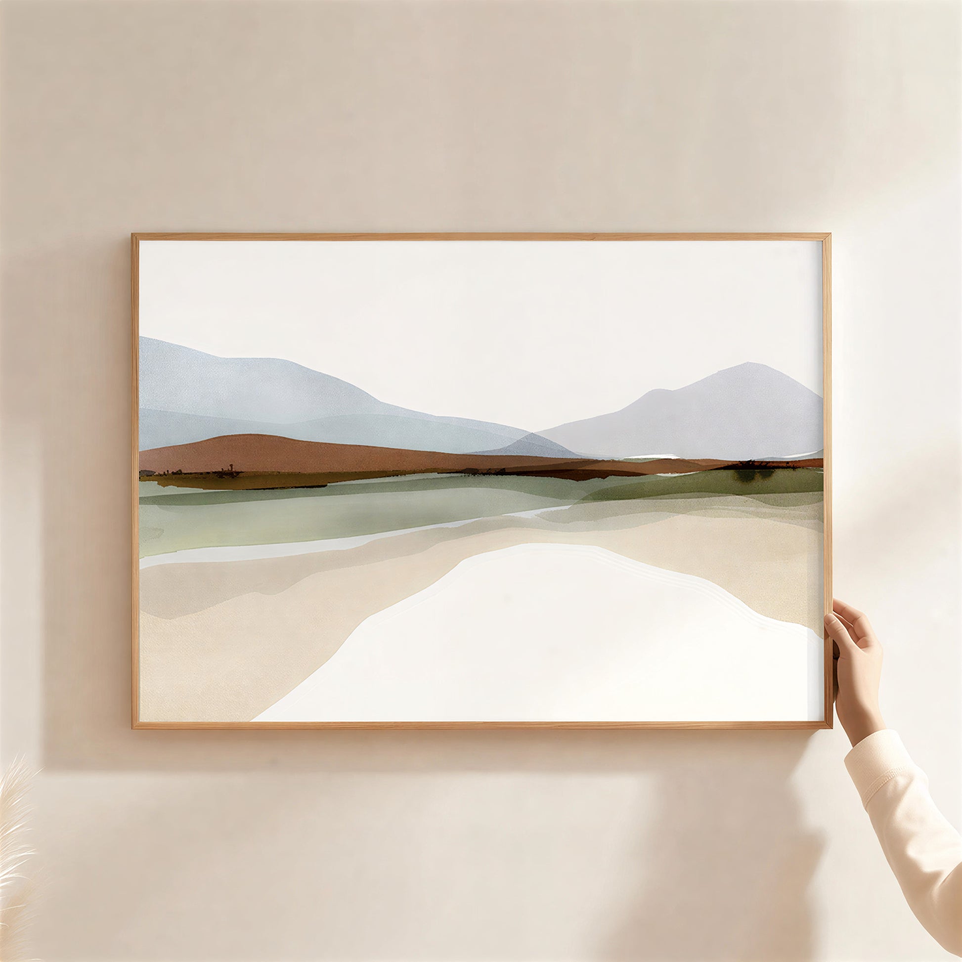 Framed landscape painting of a desert scene with mountains on a beige wall.
