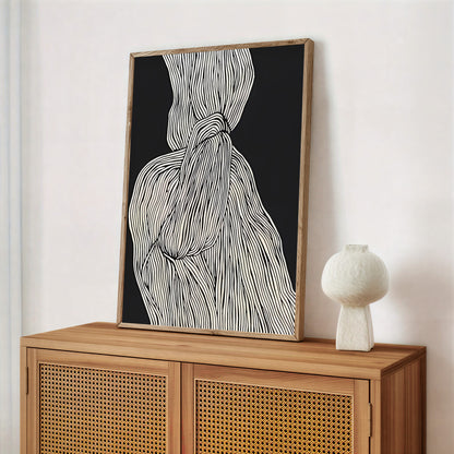 Framed abstract artwork on a wooden cabinet with a white vase.
