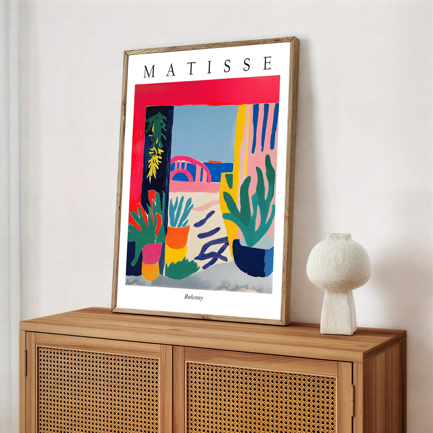 Framed Matisse artwork on a wooden cabinet with a white vase.