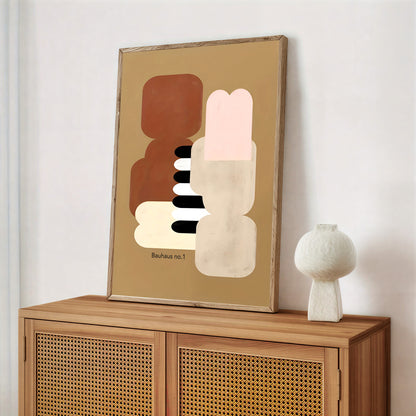 Abstract art piece on a wooden cabinet with a white vase.