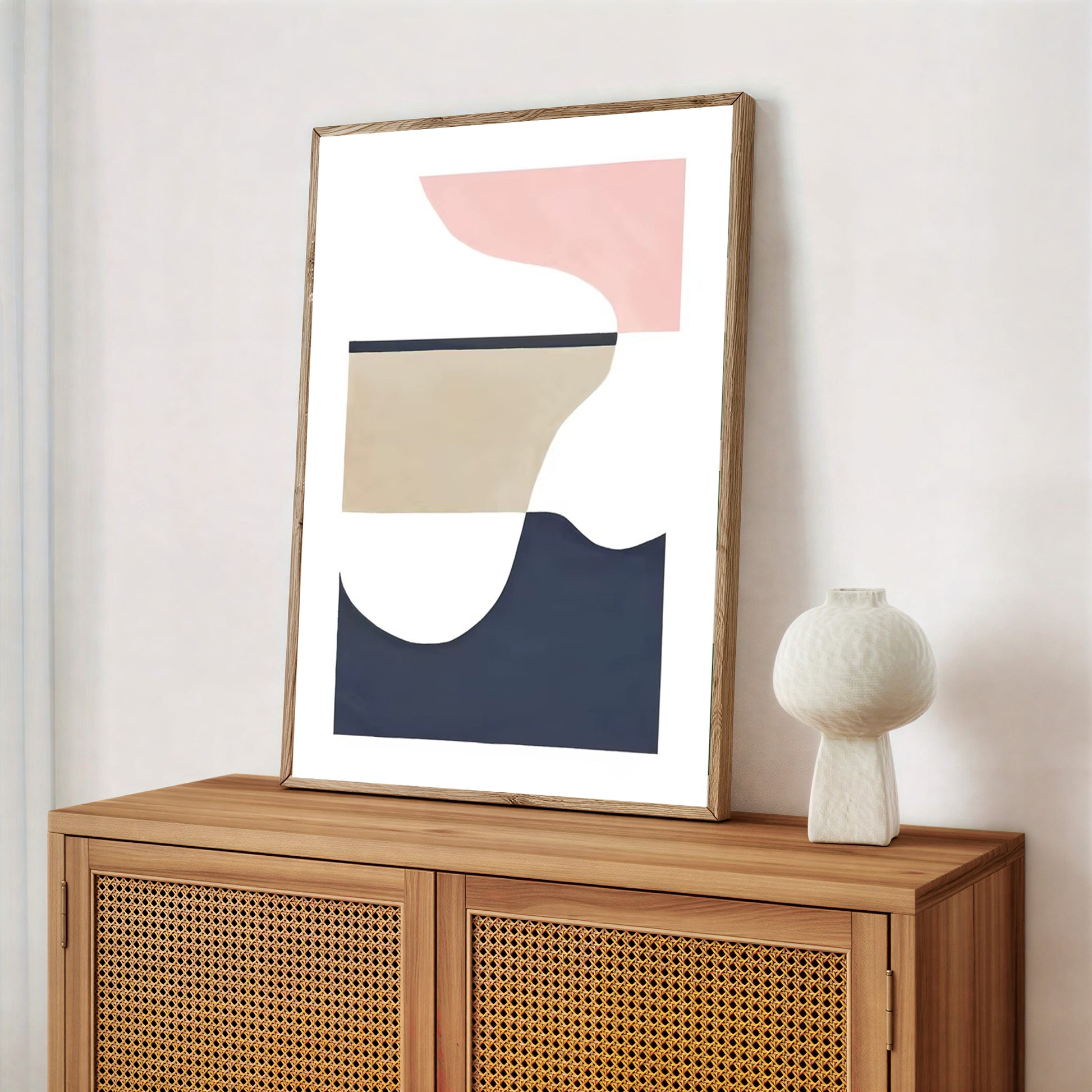 Scandinavian wall art print minimalist design in a wooden frame on a wooden cabinet with a white vase.