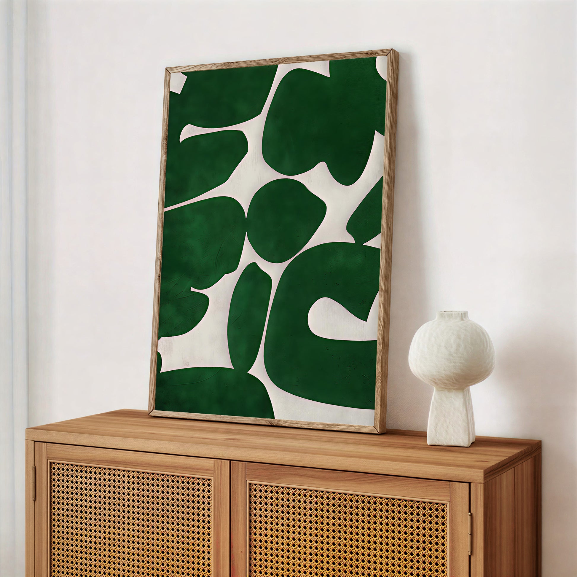 Framed green leaf-patterned artwork on a wooden cabinet with a white wall background