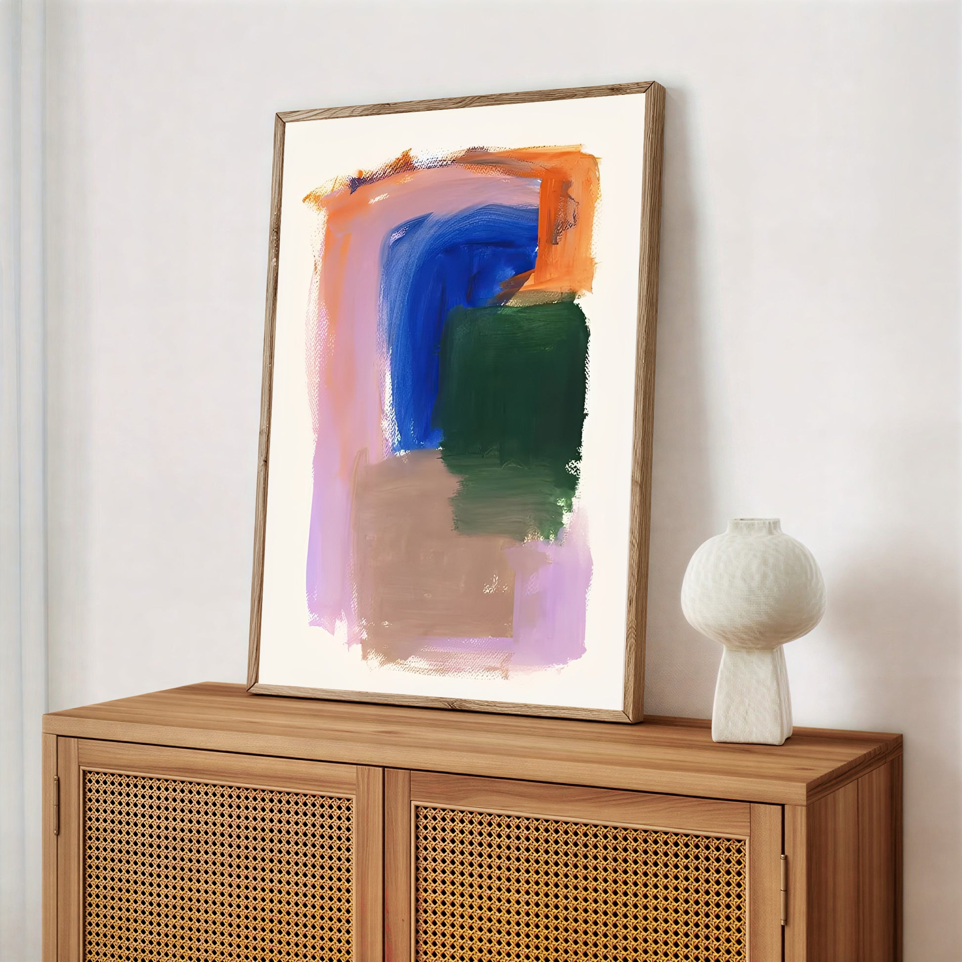 Abstract painting on a wooden cabinet with a white vase.
