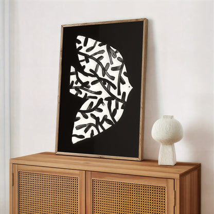 Framed abstract art piece on a wooden cabinet with a white vase.