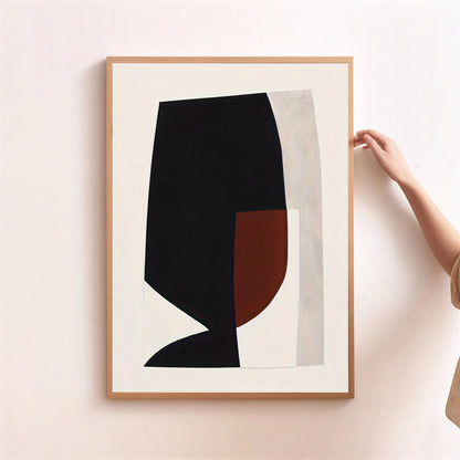 Framed abstract art piece with black and brown shapes on a light background