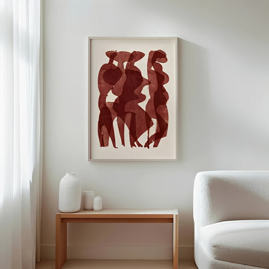 Framed abstract art of three figures on a wall above a side table with decorative items.