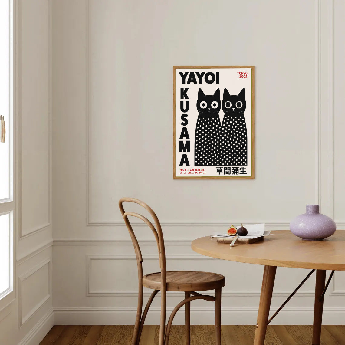 Framed Yayoi Kusama Inspired Black Cat Poster on a wall above a wooden table with a chair.