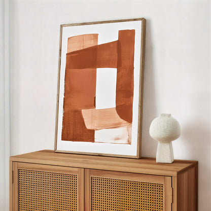 Abstract art piece on a wooden cabinet with a white vase.