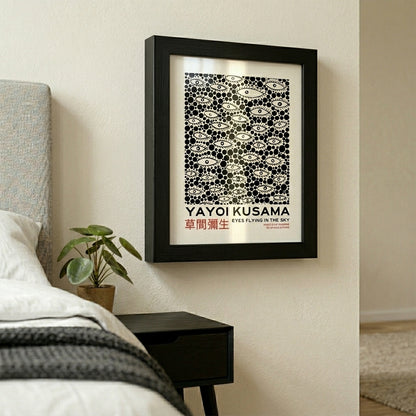 Framed artwork by Yayoi-Kusama Inspired Poster Dots and Eyes on a wall sided to bed