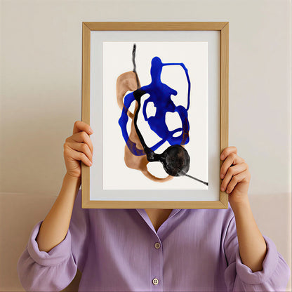 Person holding a framed abstract art piece with blue and black abstract design.