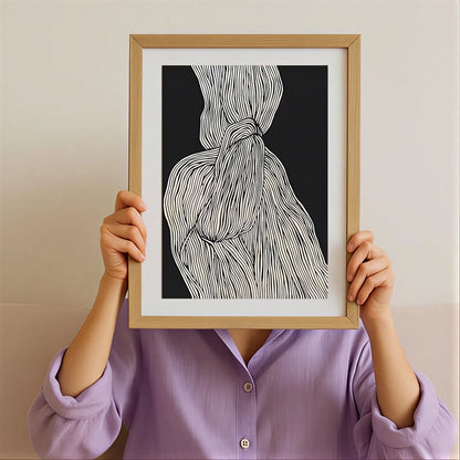Person holding a framed black and white abstract art print against their face.