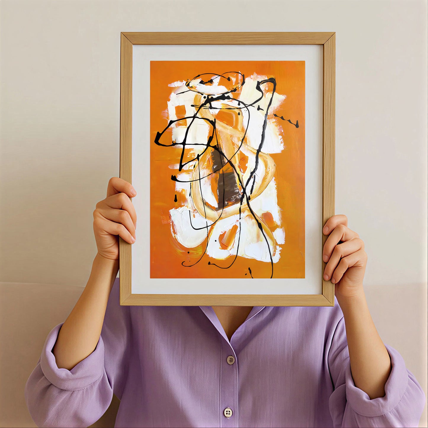 Person holding a framed abstract artwork with orange, white, and black colors against a beige background.