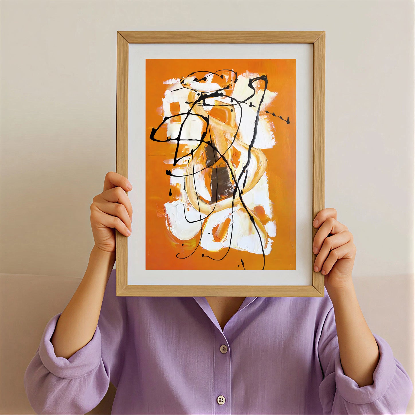 Person holding a framed abstract artwork with orange, white, and black colors against a beige background.