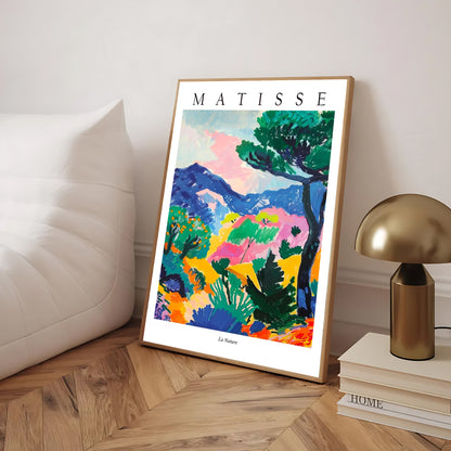 Framed Matisse artwork on a wooden floor with a lamp and books in the background