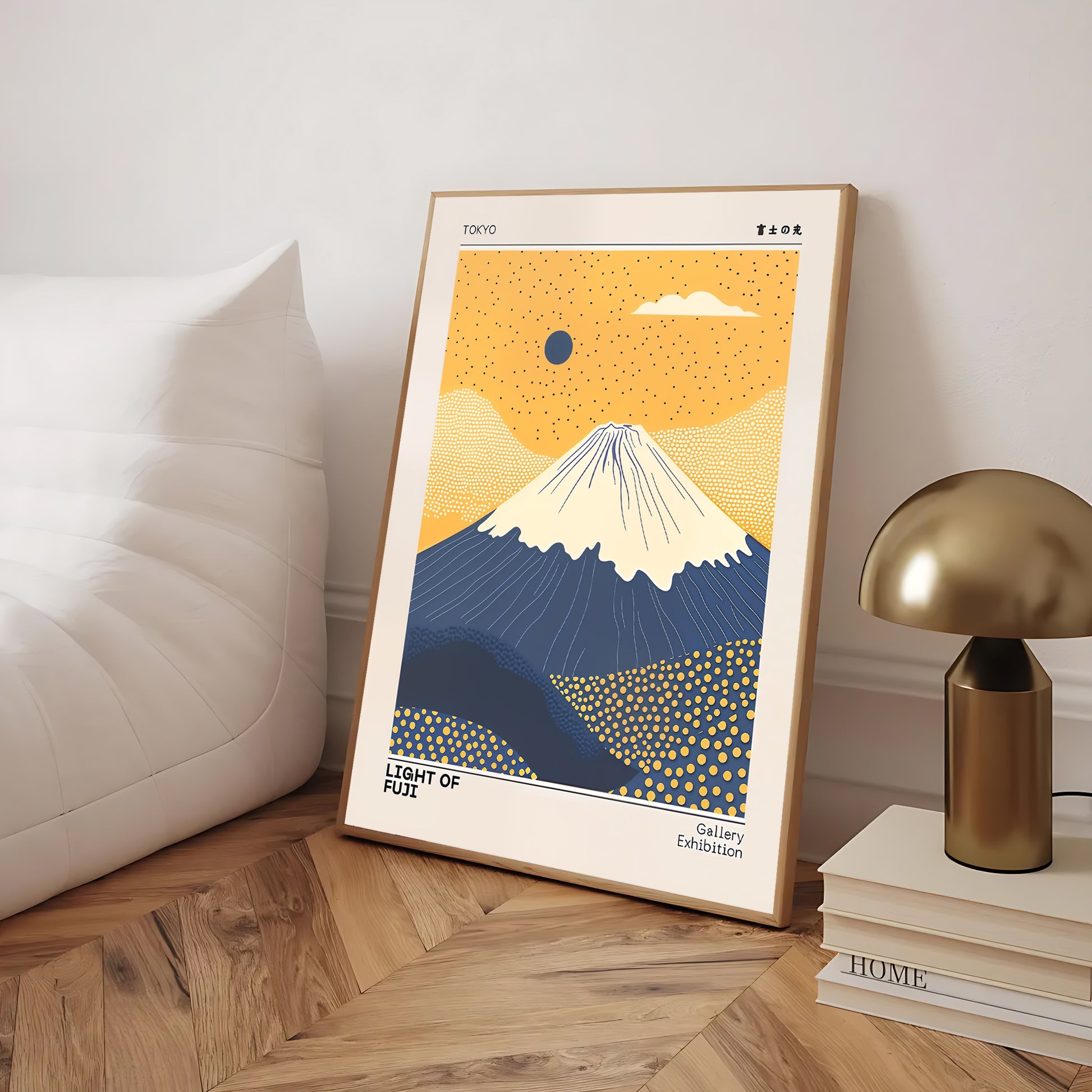 Framed artwork of Mount Fuji on a wooden floor with a lamp and books in the background.