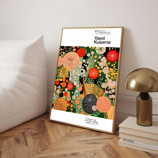 Framed artwork by Yayoi Kusama on a wooden floor with a lamp and books in the background.