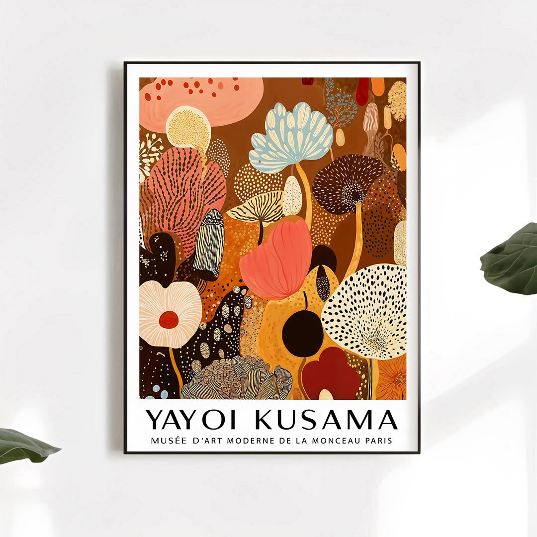 Framed artwork by Yayoi Kusama on a white wall with leaves.