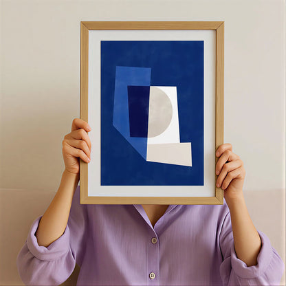 Person holding a framed abstract art piece with geometric shapes against a plain background