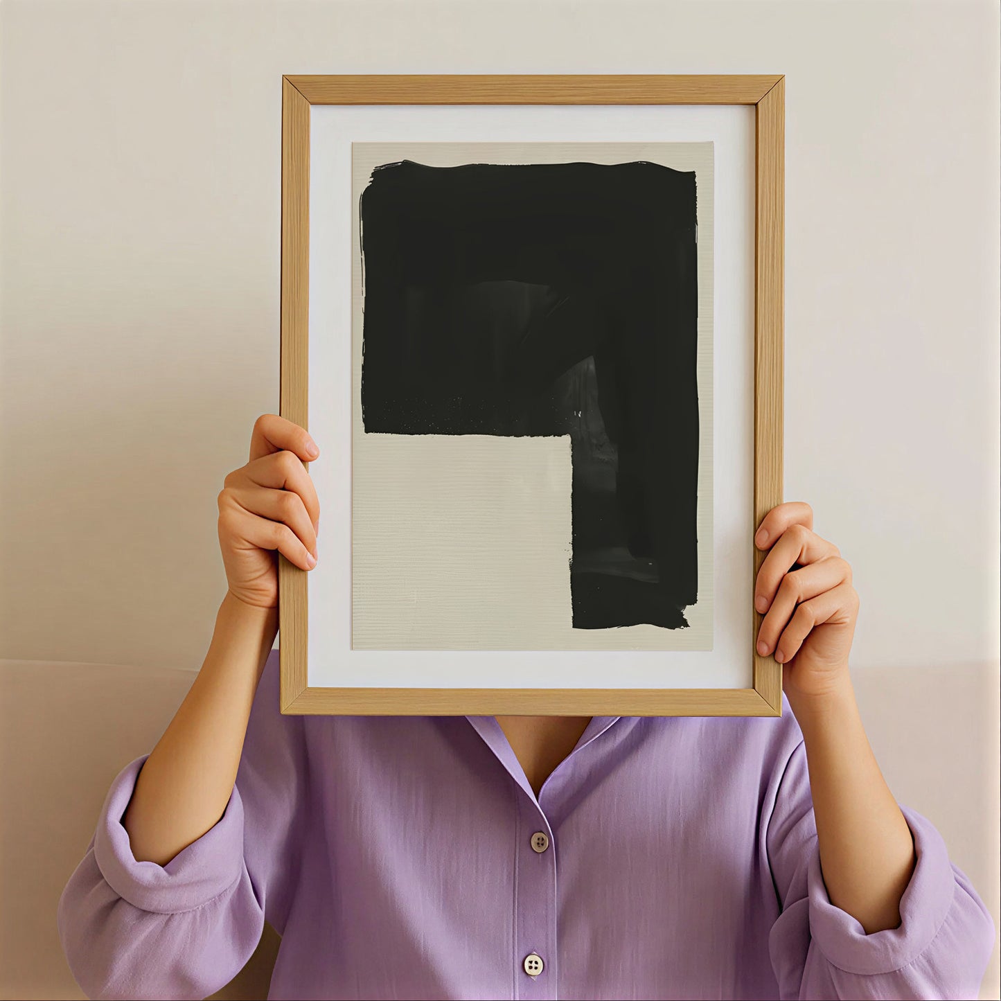 Person holding a framed abstract artwork with a plain background