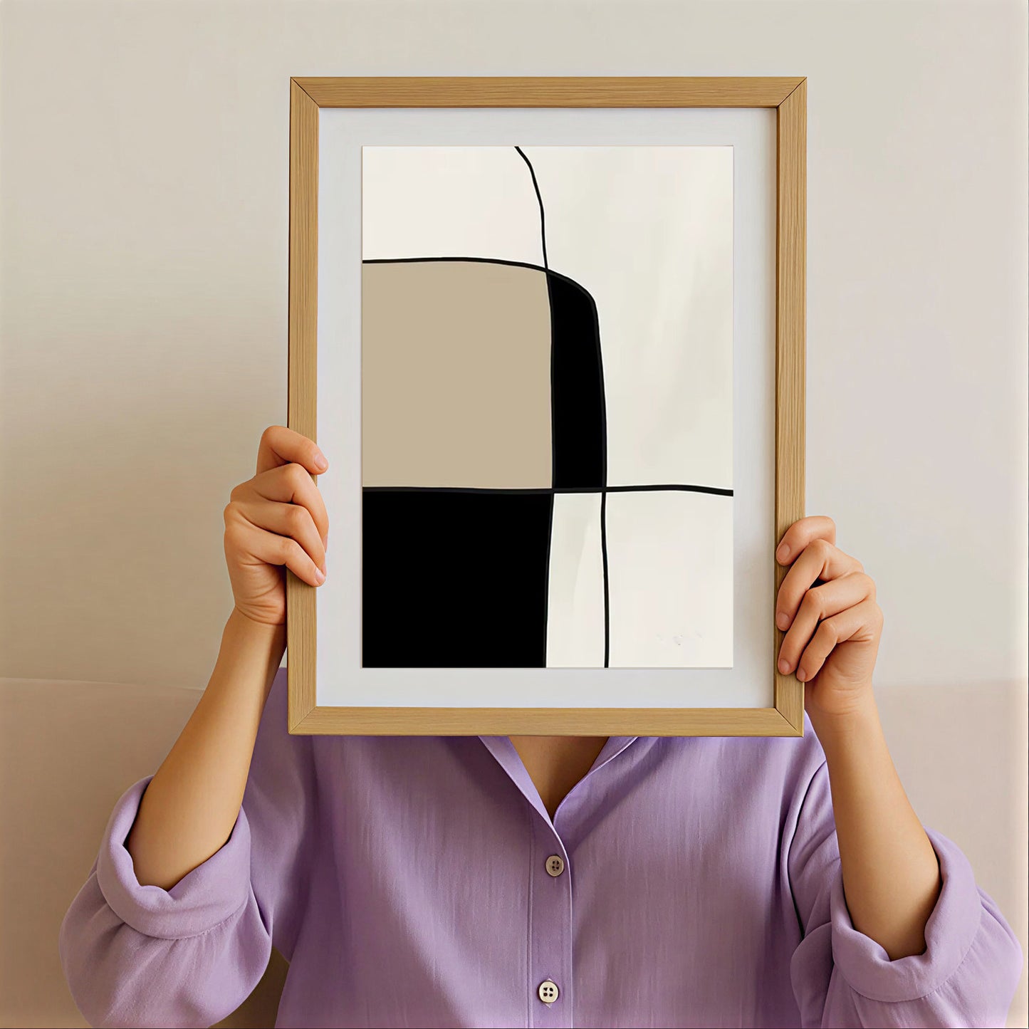 Person holding a framed abstract art print with geometric shapes against a plain background