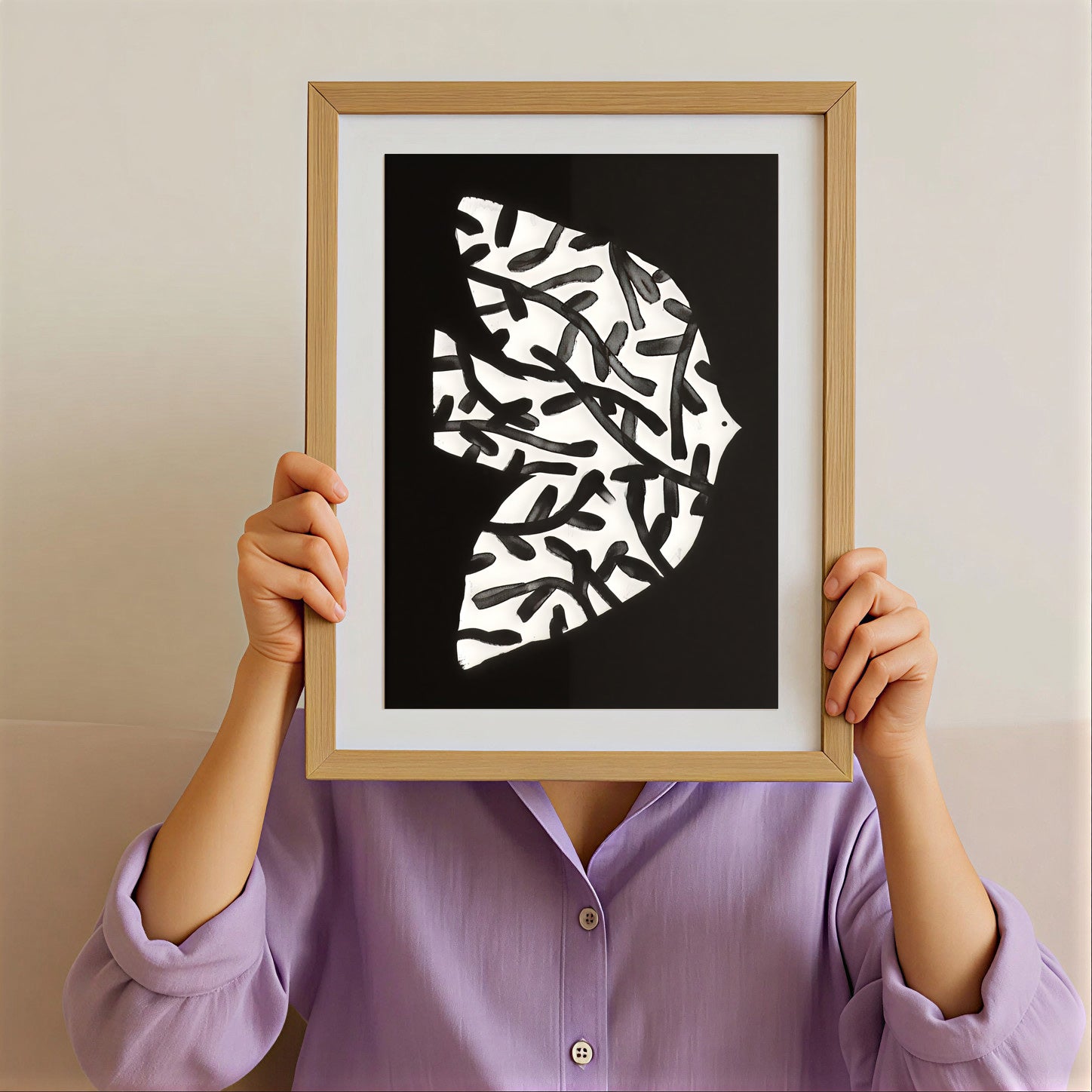 Person holding a framed abstract art print with a black background and white patterns.