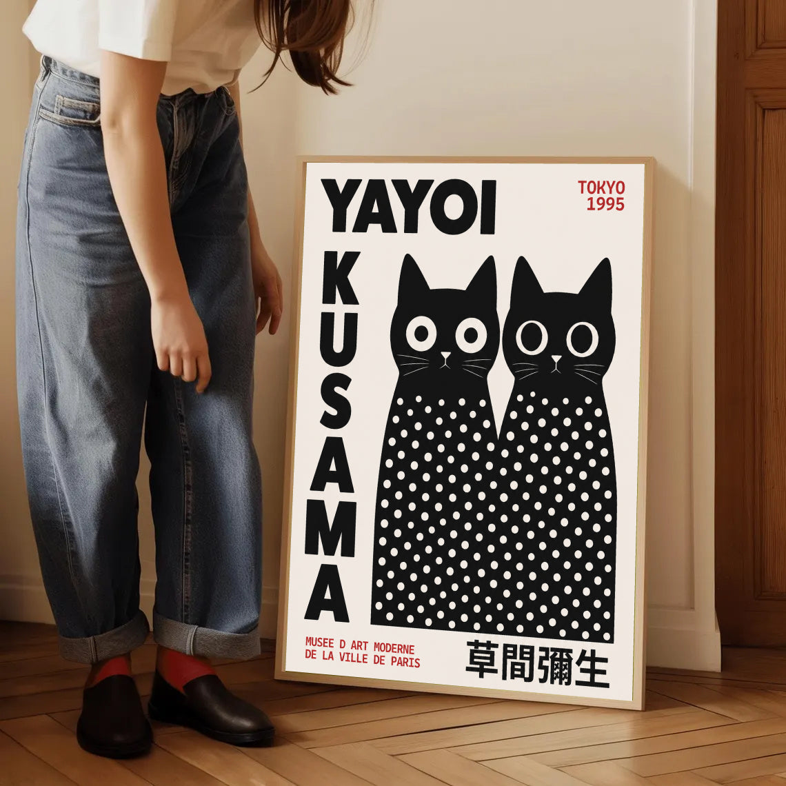 Person standing next to a framed artwork by Yayoi Kusama Inspired Black Cat Poster with white polka dots.