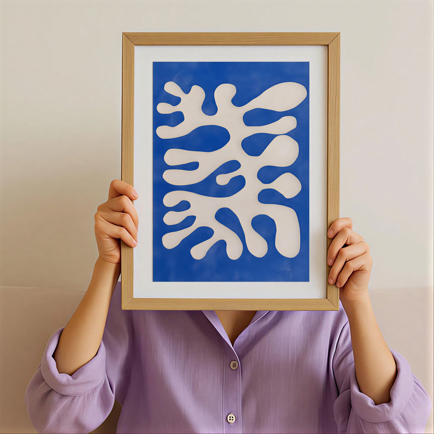 Person holding a framed abstract artwork with blue and white design against a plain background