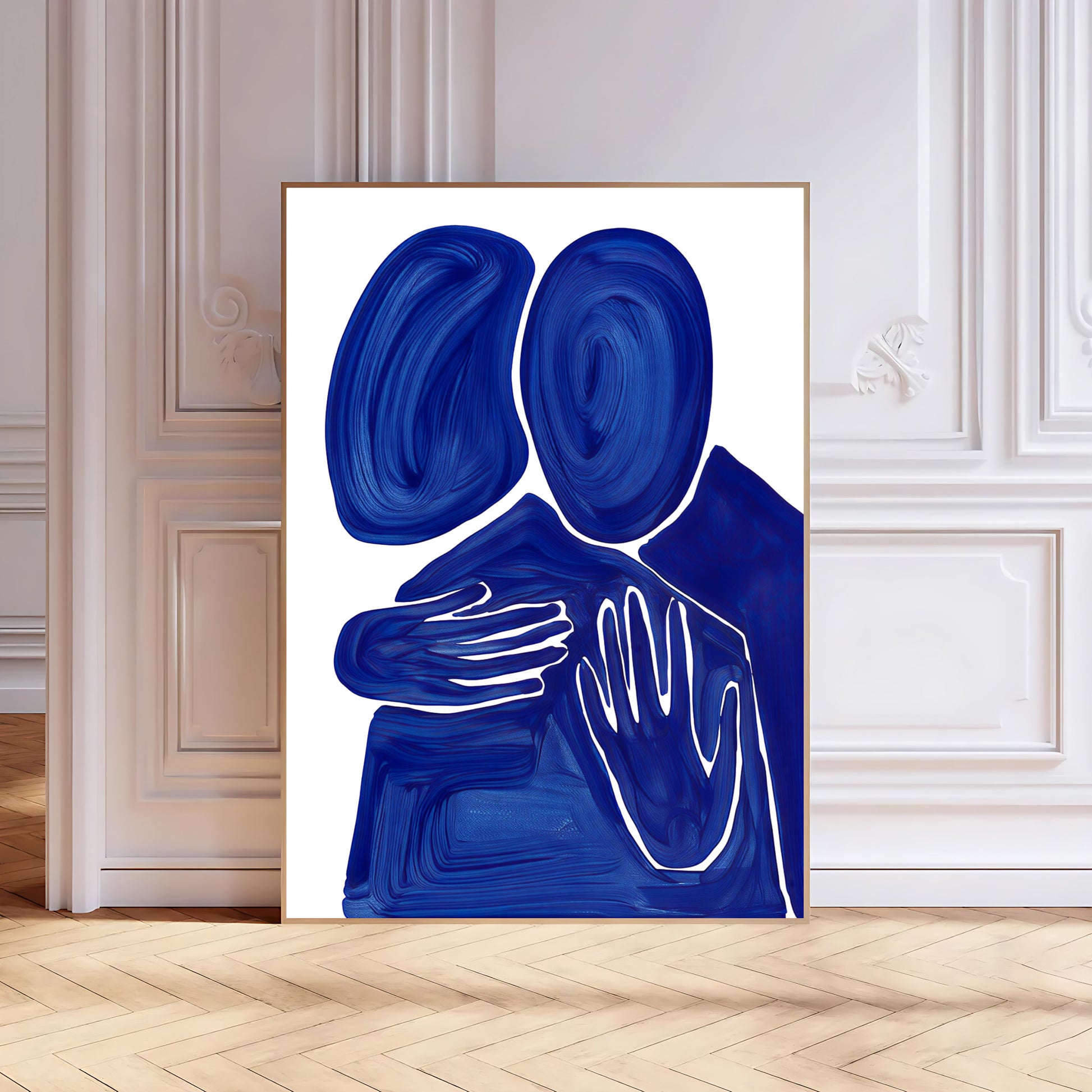 Abstract art print of two blue figures embracing on a white background, framed in a modern interior setting.