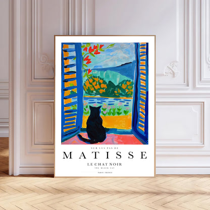 Framed Matisse art print of a cat by an open window in a room with wooden floor and white walls.