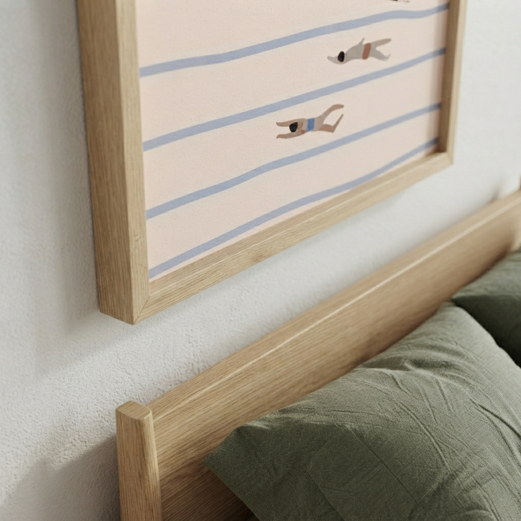 A light oak wood bed frame with a matching headboard and green pillows, shown below a framed Minimalist Swimming Pool Art Print for modern living room with abstract pool artwork, featuring minimalist figures swimming in blue horizontal stripes on a pale pink background.
