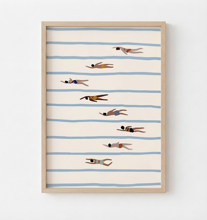 Framed wall art featuring a minimalist illustration of swimmers on horizontal blue stripes against a warm cream background, shown in a light wood frame on a white wall.