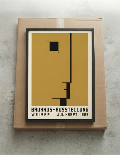 A framed  Minimalist Geometric Bauhaus Exhibition Art Print – Bauhaus Inspired Modern Wall Décor by PrintHaus featuring a minimalist black geometric design on a mustard yellow background, mounted on a brown cardboard box against a textured gray wall.