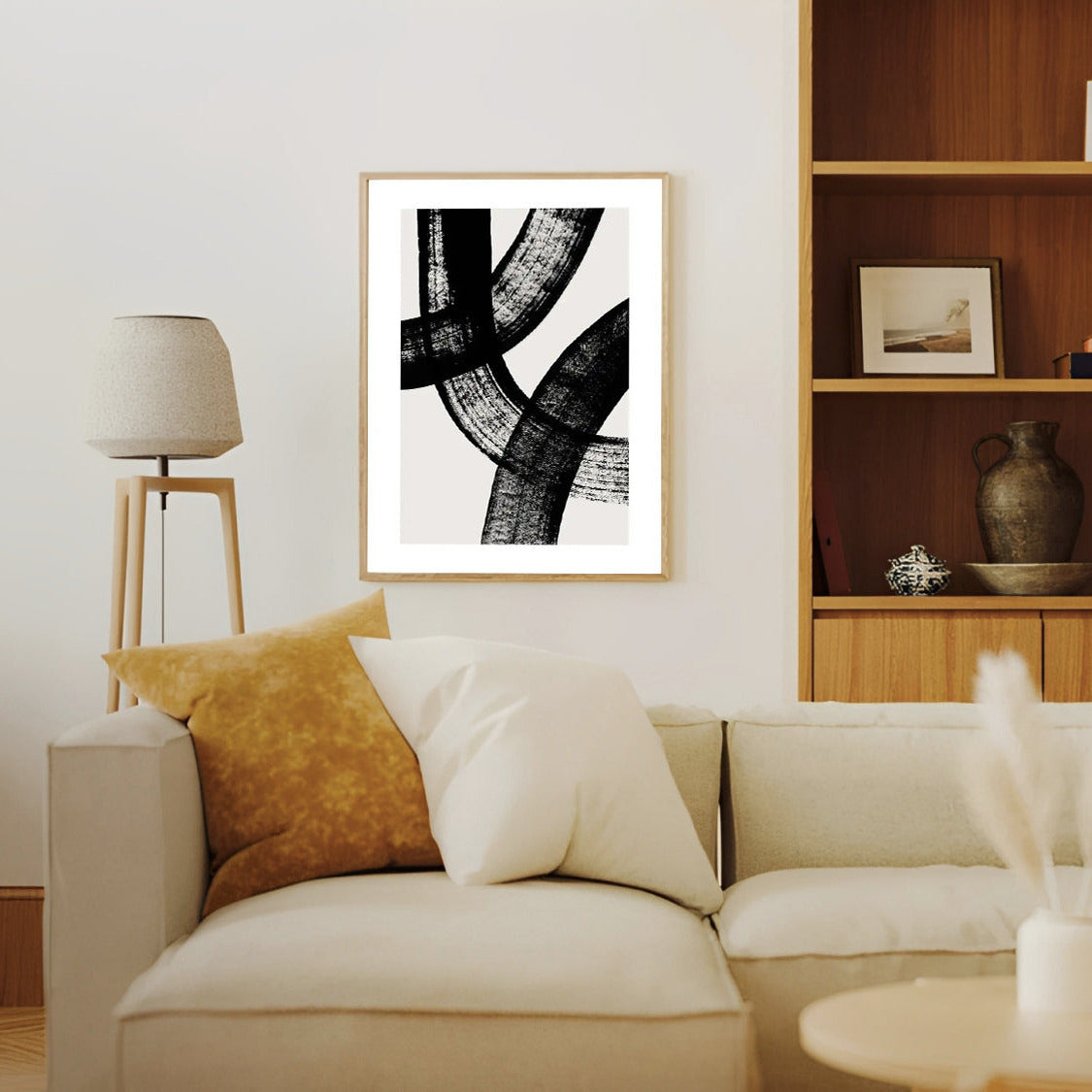 Living room with a beige sofa, abstract art on the wall, and wooden shelves.