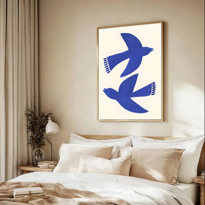 Modern bedroom with a bed, decorative pillows, and a framed abstract artwork of blue birds on the wall.