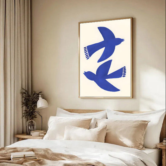 Modern bedroom with a bed, decorative pillows, and a framed abstract artwork of blue birds on the wall.