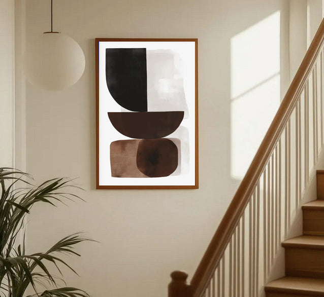 Abstract art piece on a wall in a home setting with a staircase and plant.