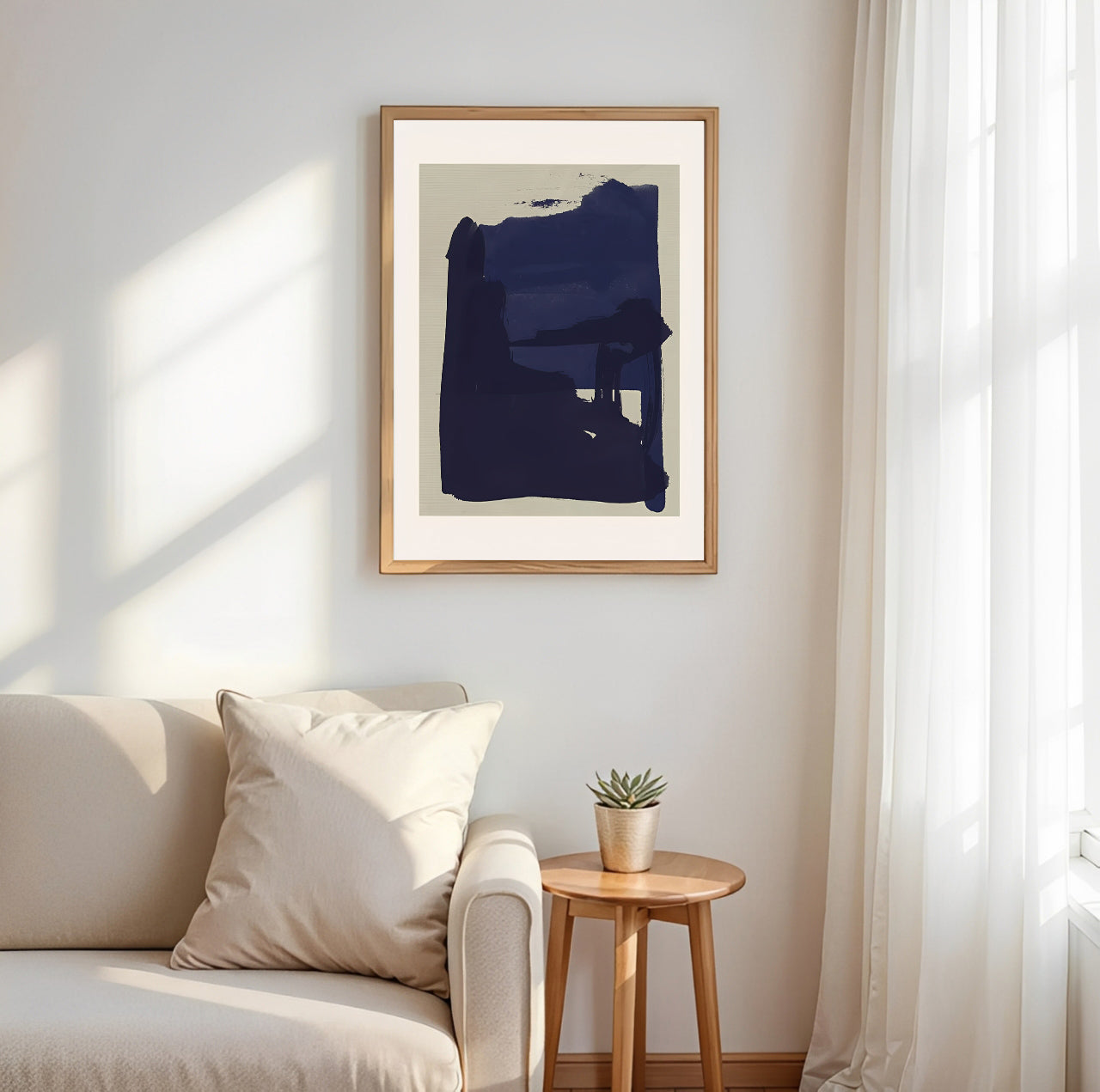 Abstract art print in a wooden frame on a wall above a sofa with natural light.